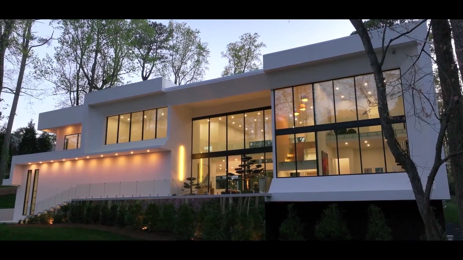 A modern luxury home lit at dusk, illustrative